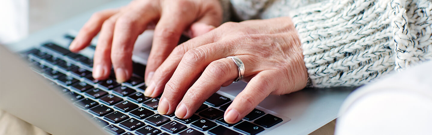Senior female typing on laptop keypad